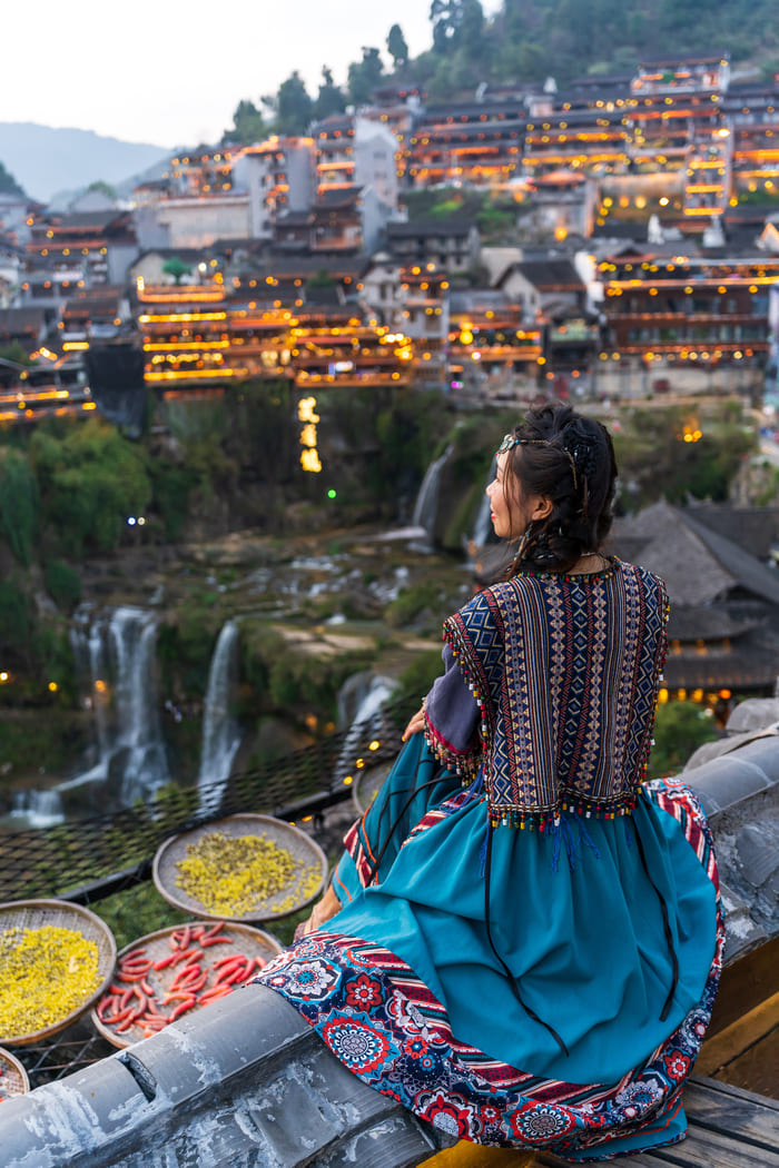 Mujer con vesgtimenta tradicional de china frente a la ciudad de Lijiang